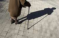 An elderly woman casts a shadow as she walks down the street in central Madrid, January 12, 2011. REUTERS/Juan Medina.