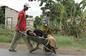 A woman suffering from the symptoms of cholera is taken in a wheelbarrow to a clinic in Harare December 12, 2008.REUTERS/Philimon Bulawayo.