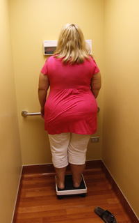 A bariatric surgery patient looks at her weight reading 296.6 lbs. at her surgeon's five days before her procedure August 25, 2010. She hoped to lose around 150 pounds due to the procedure over the next year. REUTERS/Rick Wilking.