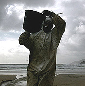 A volunteer carries spilled oil on a beach at Estorde in the Spanish northwestern region of Galicia on December 27, 2002. France and Spain may soon have to fight together against the ecological disaster as high winds drive a massive oil slick from the Bahamas-registered sunken tanker Prestige toward French waters. REUTERS/Marcelo Del Pozo