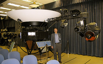 Krimigis standing by the Voyager proof-test model spacecraft on display at the Jet Propulsion Laboratory. The LECP (Low Energy Charged Particle) instrument for which he is Principal Investigator can be seen above his left shoulder.