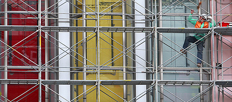 A construction worker climbs a scaffolding outside a shopping centre under renovation in Taipei March 22, 2011. REUTERS/Nicky Loh.