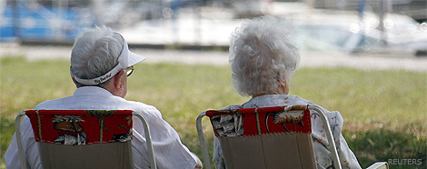 An elderly couple sit on a bench next crocus flowers in a park in Duesseldorf March 17, 2010. REUTERS/Ina Fassbender.